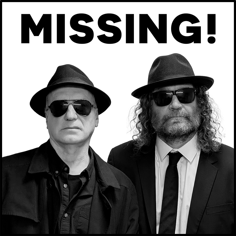 Two men in dark suits wearing hats and sunglasses